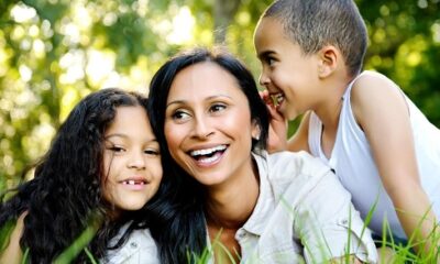 A woman and two kids sitting in the grass