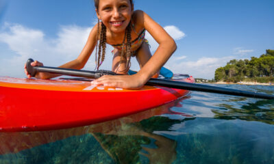 A girl on a paddleboard looks into the camera.