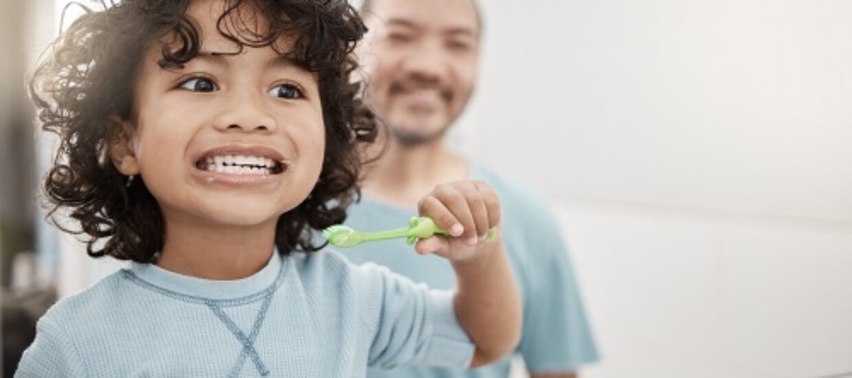 Shot of an adorable little boy brushing his teeth in a bathroom with his father at home
