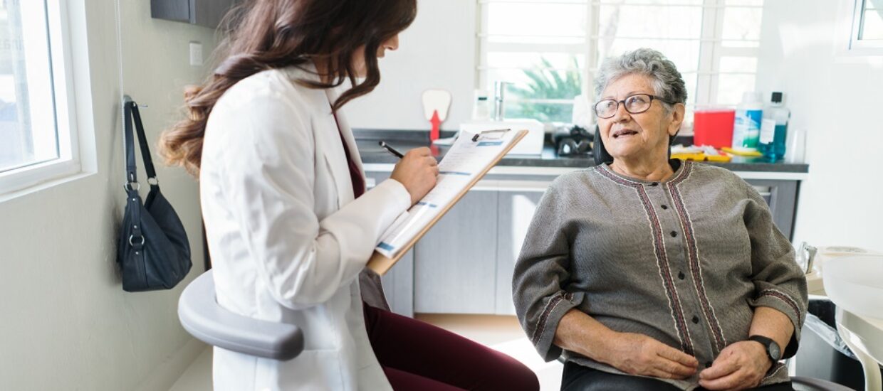 Female dentist writing information about senior patient
