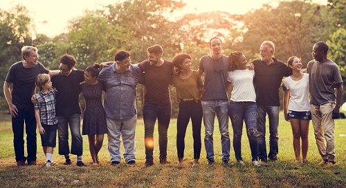 Partners standing in a grassy field in a line arms around each other