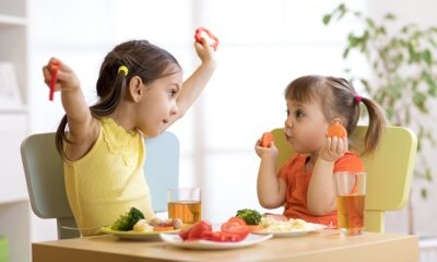 Two little girls eating healthy foods and juice with their meal