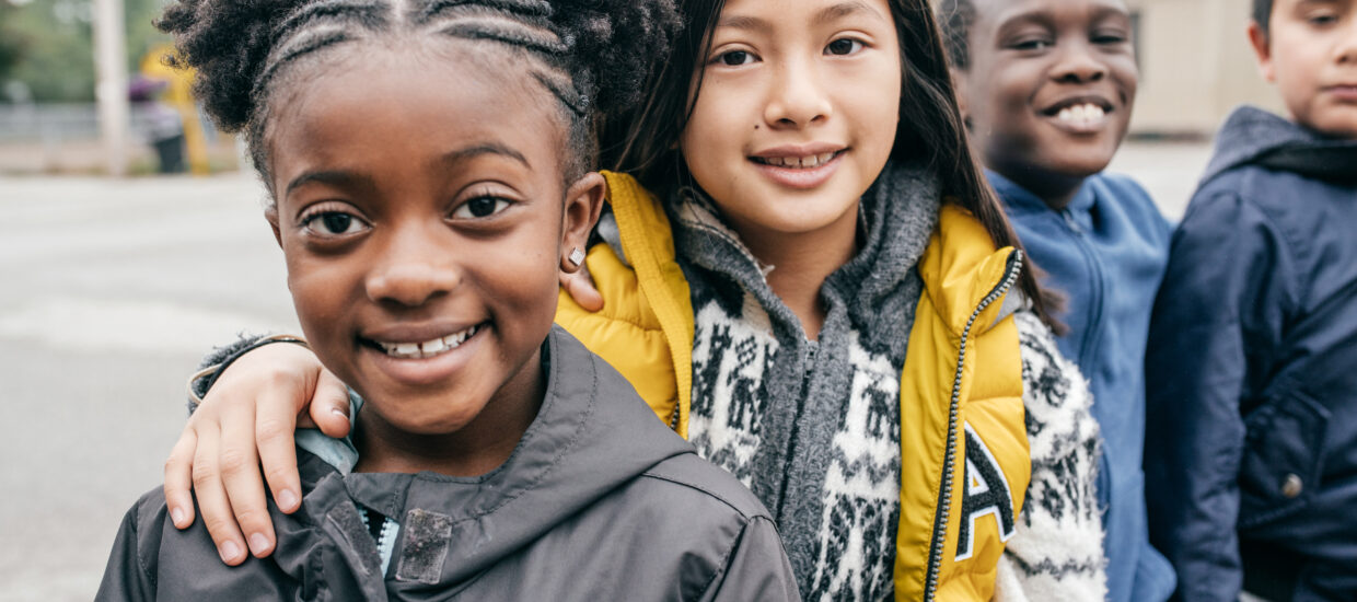 Children standing on a playground smiling