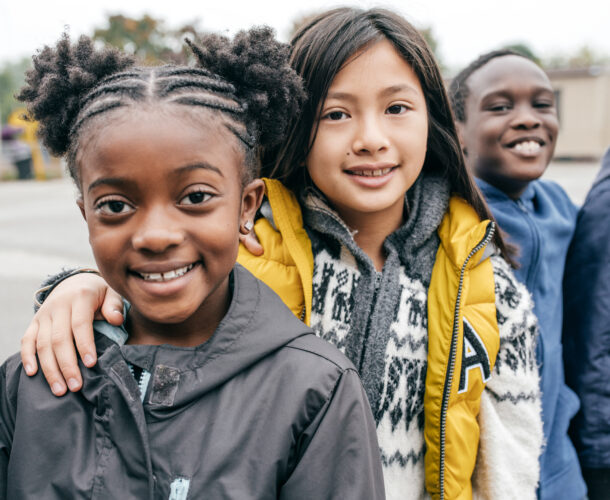 Children standing on a playground smiling