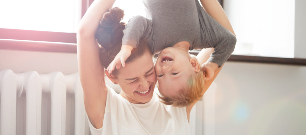 Mother holding child upside down, both smiling
