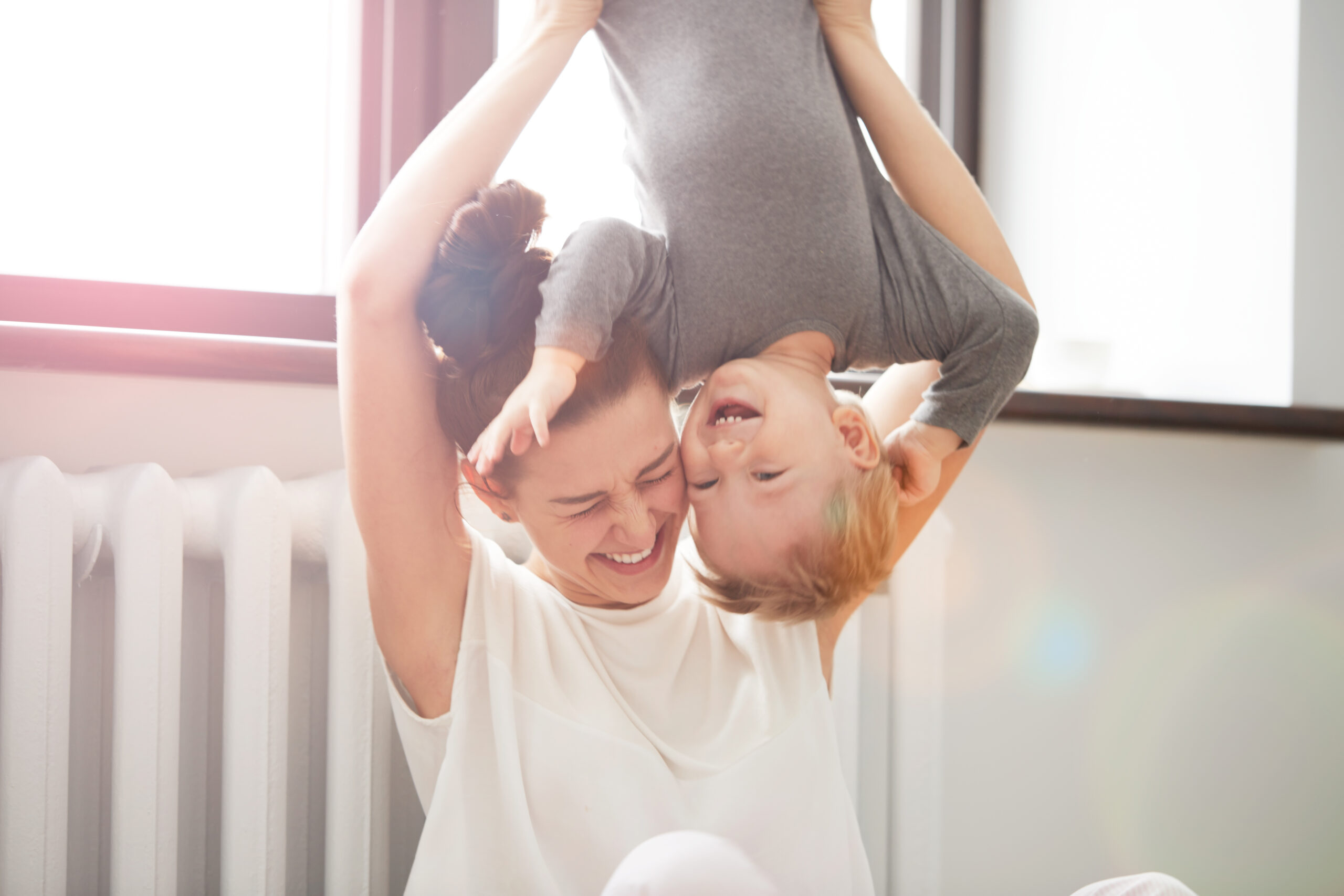 Mother holding child upside down, both smiling