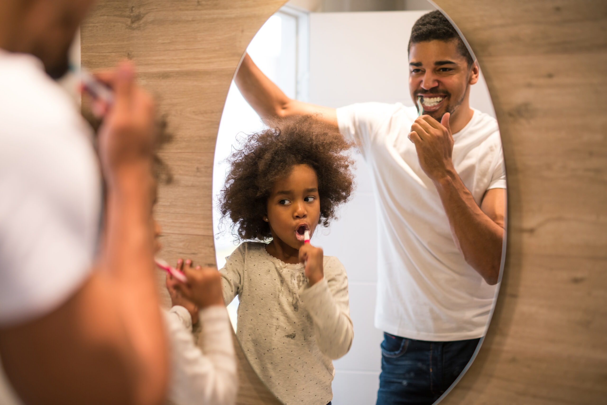 Parent and child brushing teeth in the mirror