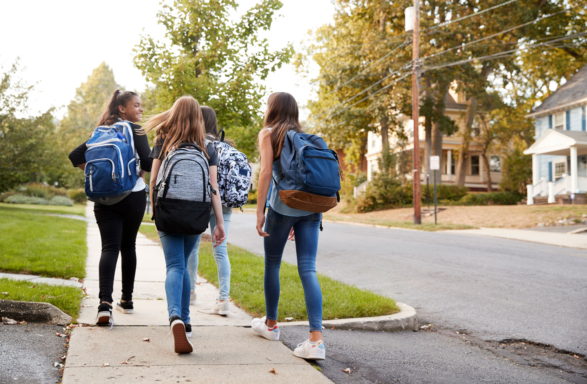 Youth with backpacks walk away on a sidewalk